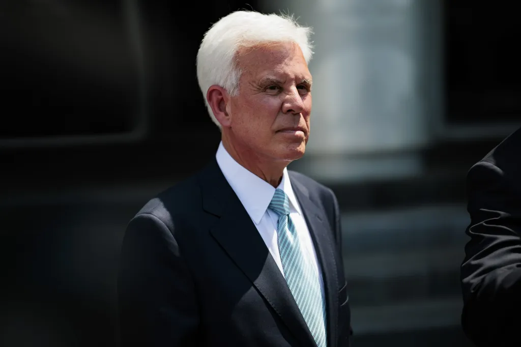 George Norcross stands outside a courthouse in a dark suit and light blue tie.