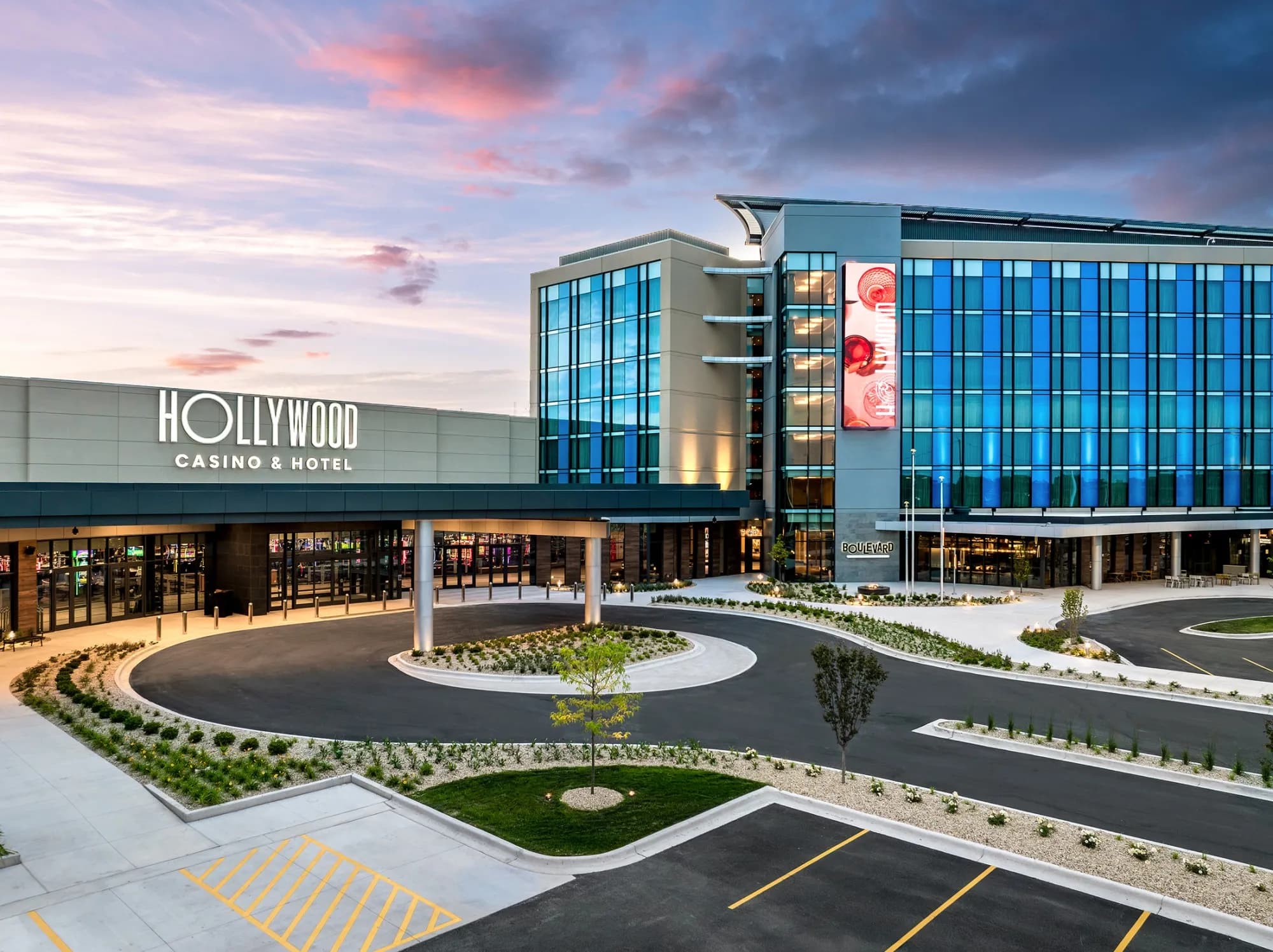 The exterior of a Hollywood Casino and Hotel property at dusk, with its entrance and parking area visible.