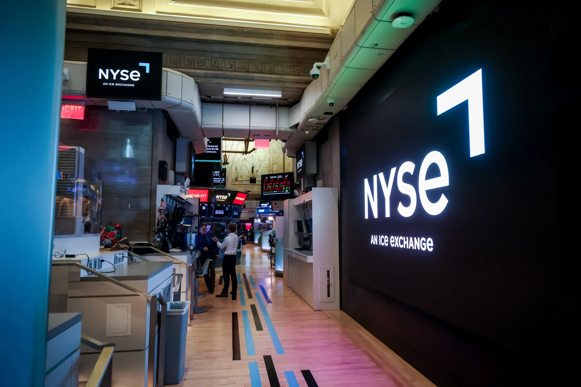 The NYSE trading floor with an illuminated ICE Exchange sign on the wall.