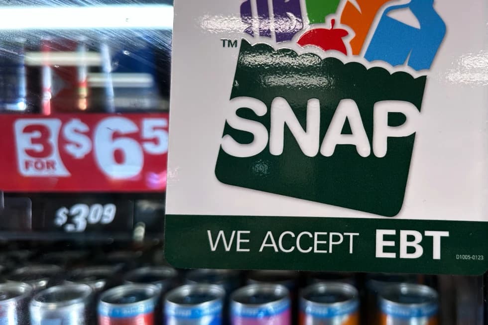 A SNAP EBT sign displayed on a store cooler, next to a price sign for beverages.