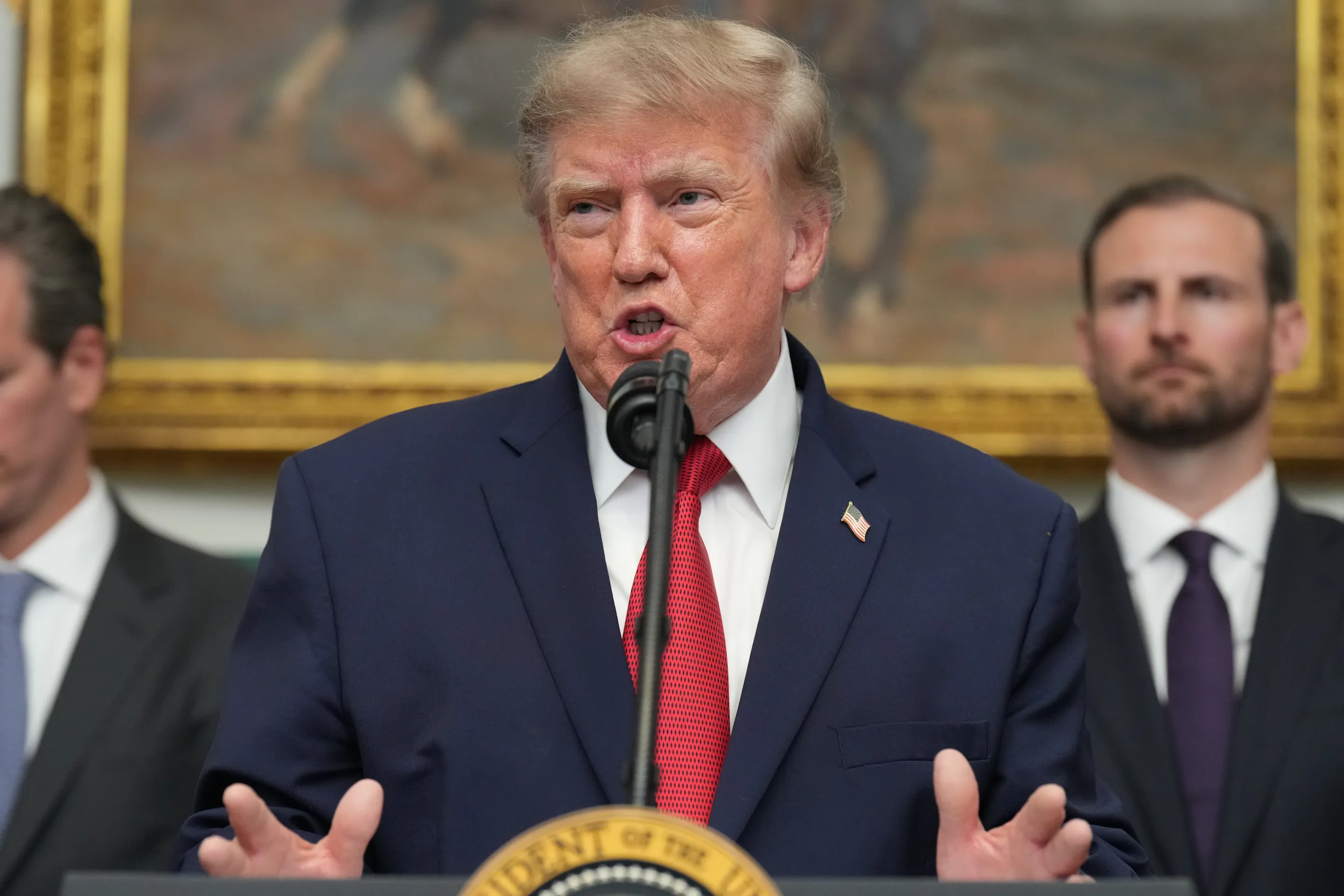 President Trump speaking at a podium in the White House during a press event.