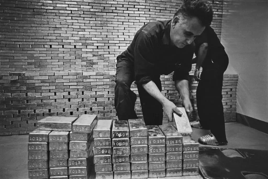 Black and white archival photo of gold bars stacked in a bank vault