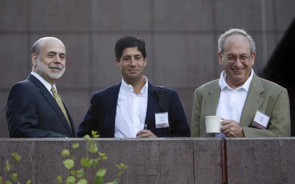 Ben Bernanke, Kevin Warsh, and Donald Kohn standing together outdoors smiling, with Kohn holding a coffee mug